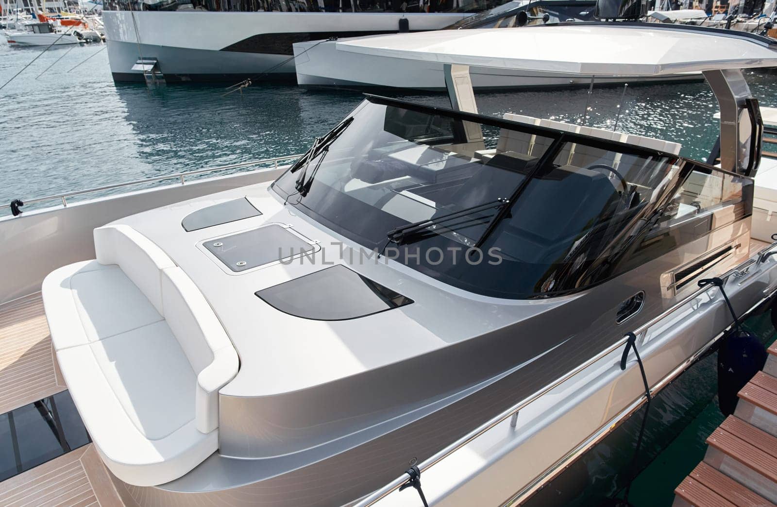 Close-up view of a relaxation area on the open teak deck of an expensive motorboat at sunny day, Monaco yacht show, large boat exhibition, wealth life, table and chairs by vladimirdrozdin