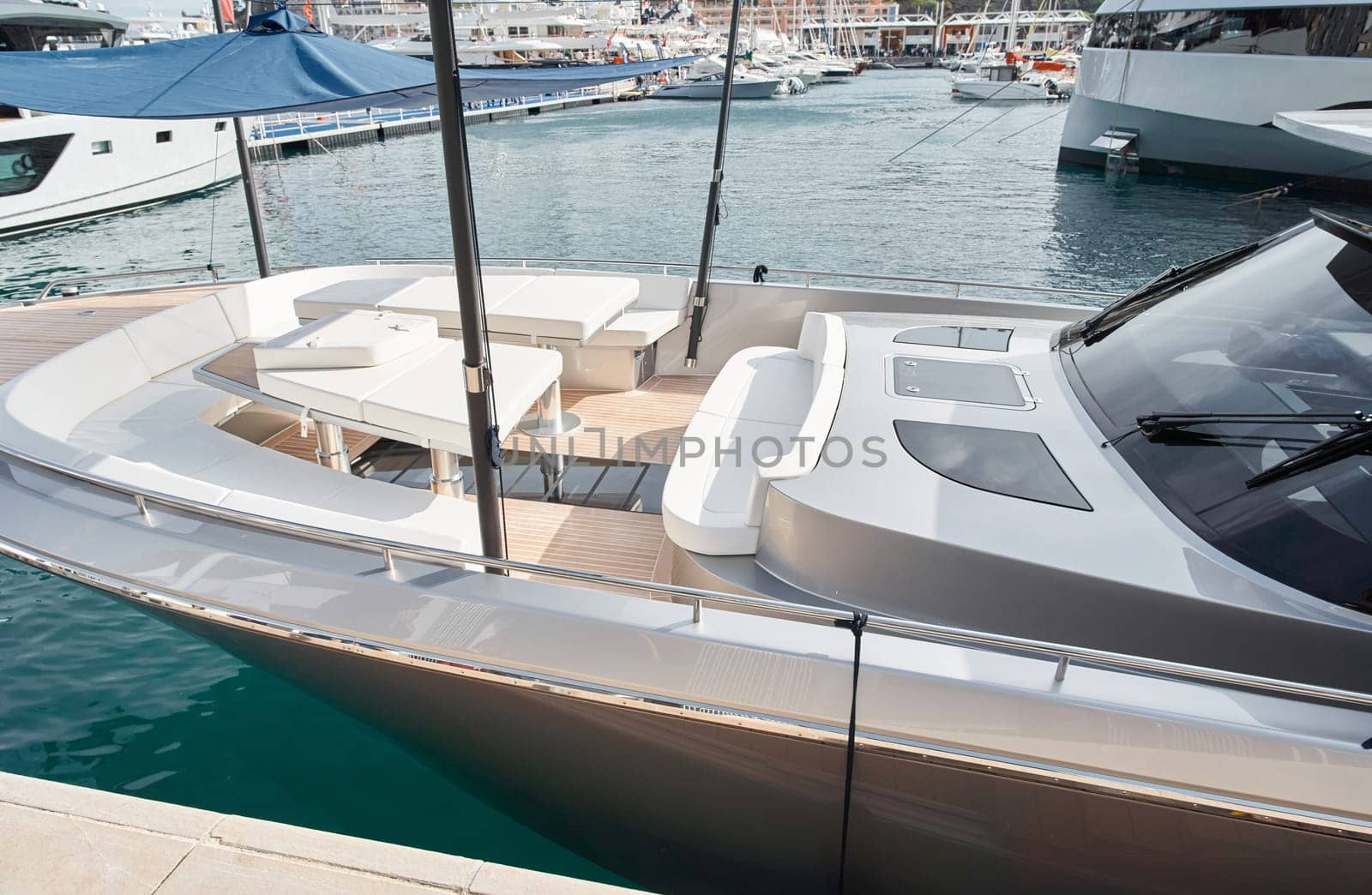 Close-up view of a relaxation area on the open teak deck of an expensive motorboat at sunny day, Monaco yacht show, large boat exhibition, wealth life, table and chairs. High quality photo