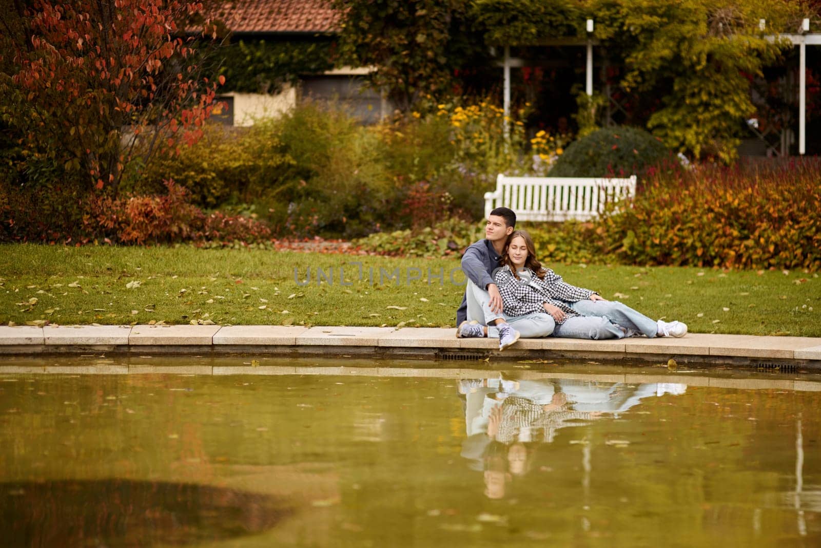 Young couple kissing and rejoices at the lake. lovely young couple kissing outdoors in autumn. Loving couple walking in nature. Autumn mood. Happy man and woman hugging and kissing in autumn. Love. Fashionable couple outdoors. Fashion, people and lifestyle. Stylish couple in autumn outfit. by Andrii_Ko