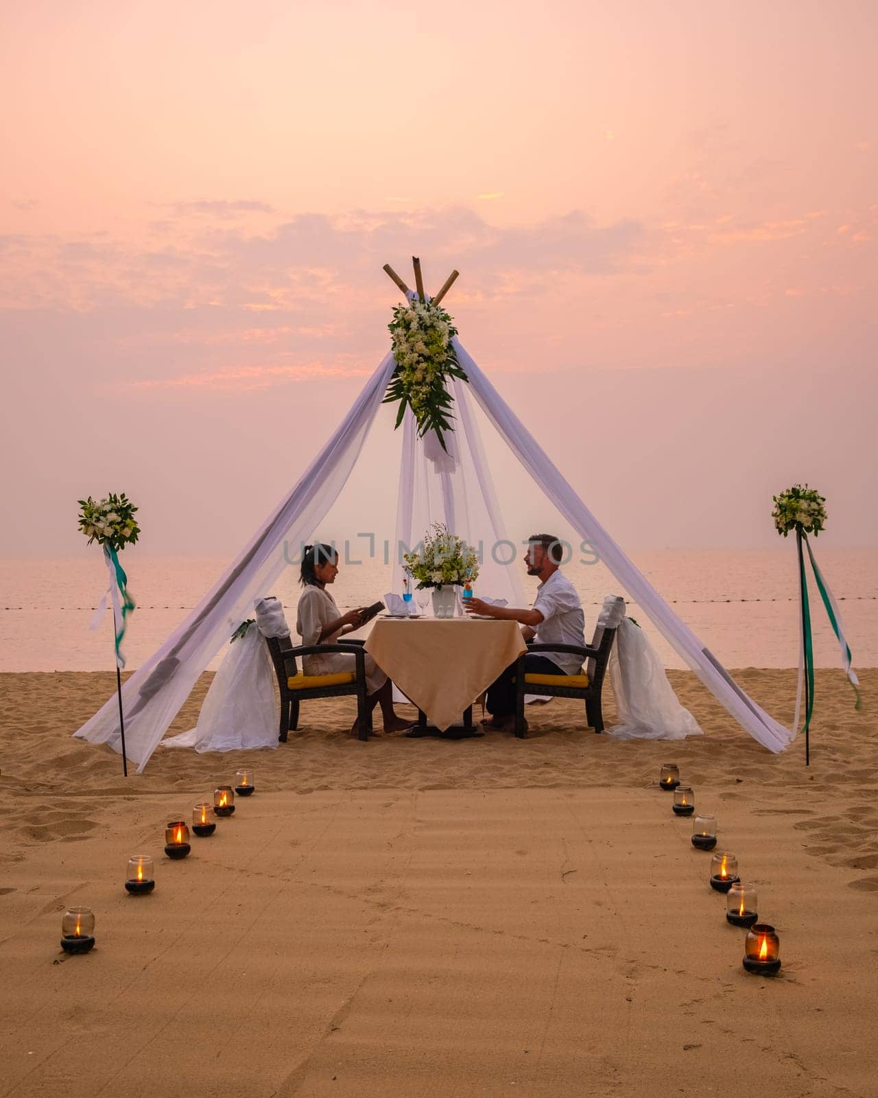 Romantic dinner on the beach in Pattaya Thailand, a couple man and woman mid age having dinner on the beach in Thailand during sunset with candles on the beach