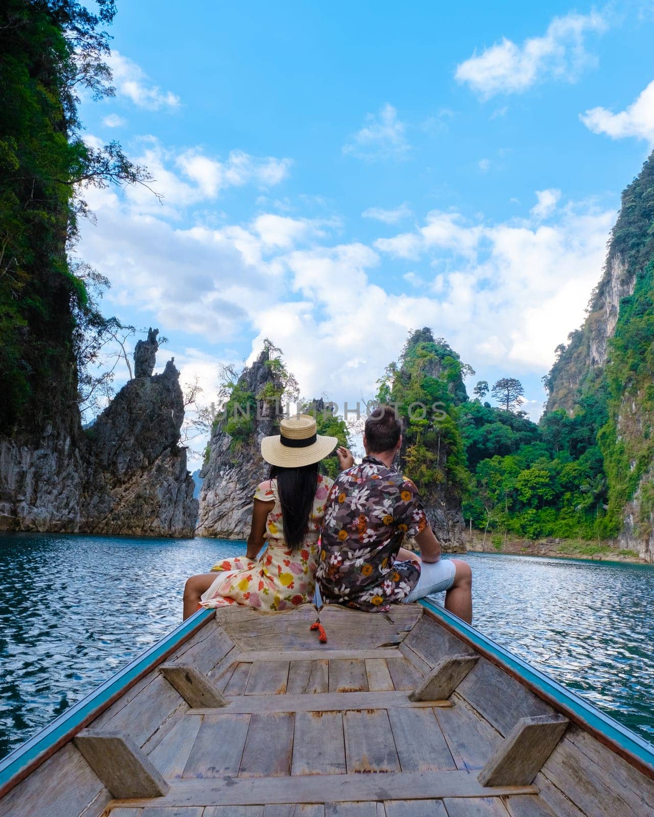 A couple of men and women in front of a longtail boat in Khao Sok Thailand, Scenic mountains on the lake in Khao Sok National Park South East Asia on a sunny day