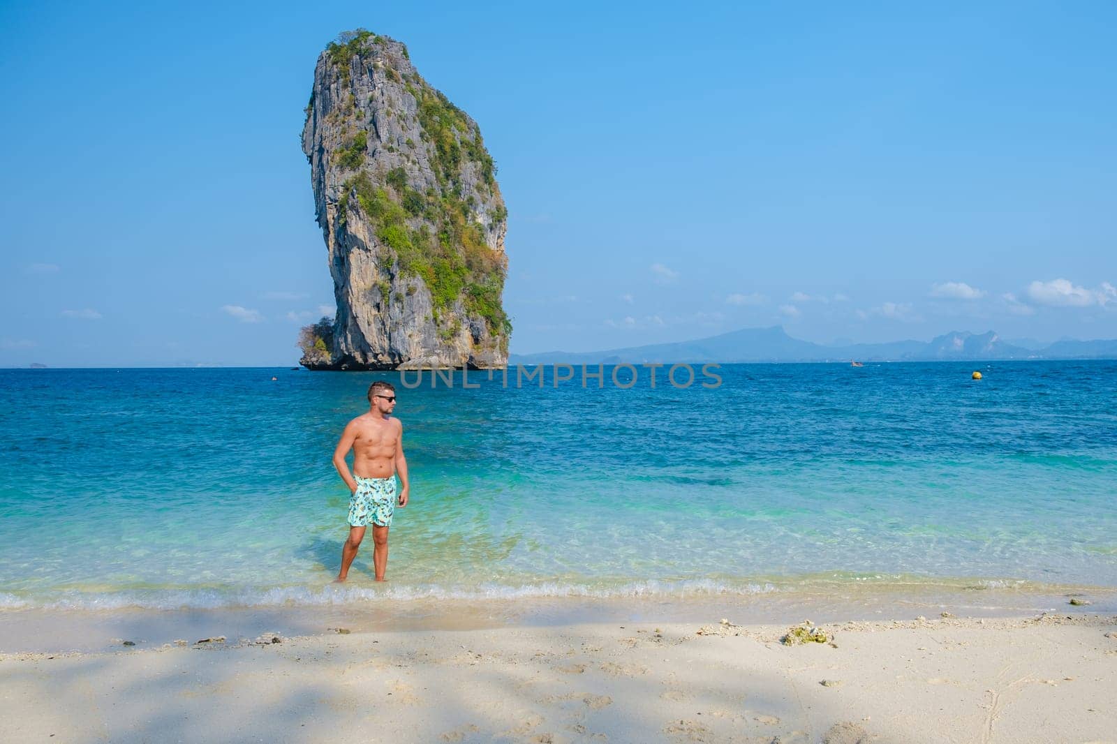 young men at Koh Poda Beach Krabi Thailand, the tropical beach of Koh Poda Island Krabi, a man in swim short walking on the beach on a sunny day