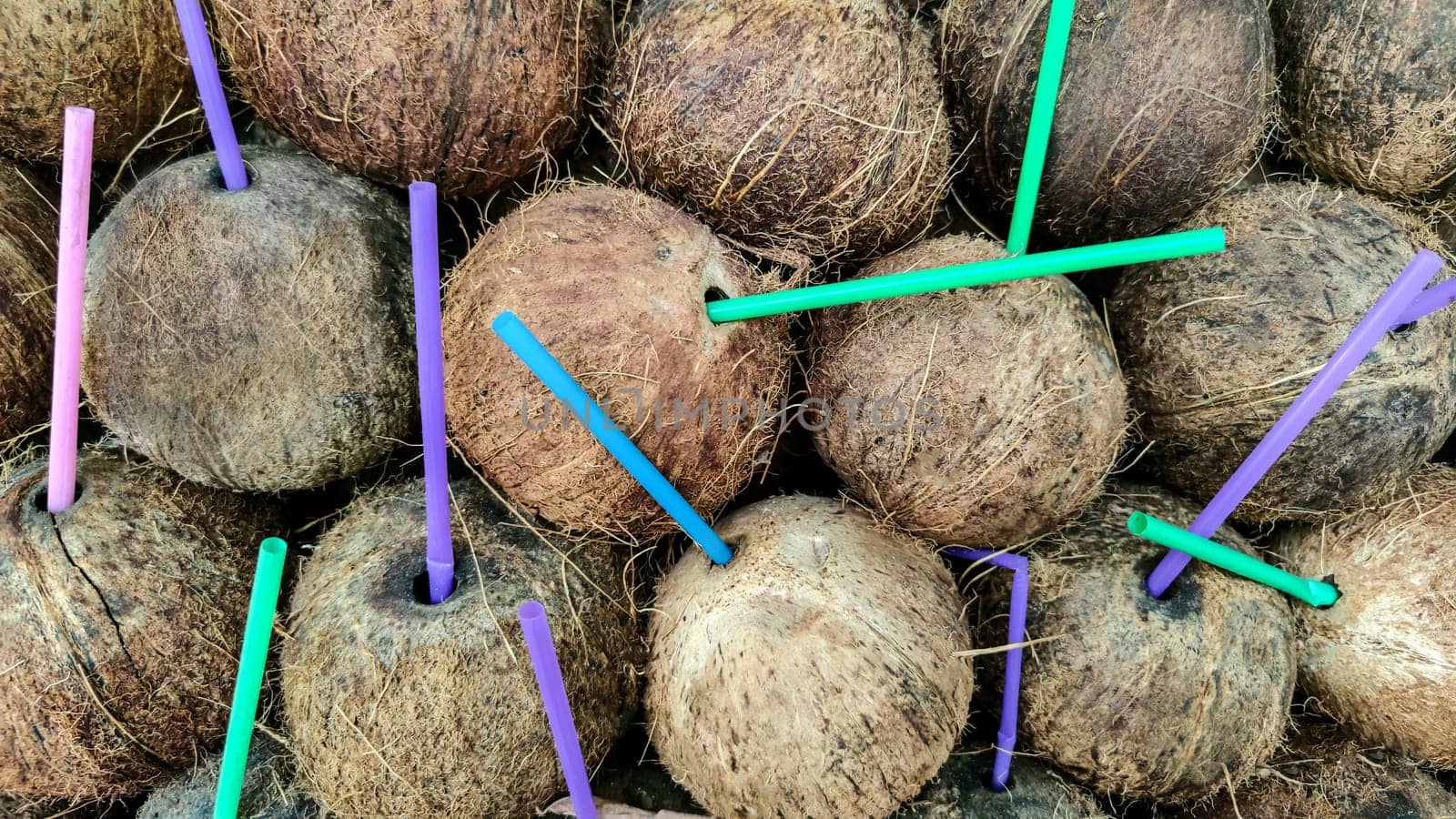 Background of coconut with colorful plastic cocktail drinking tubes.