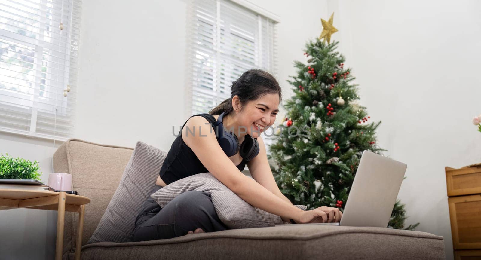 Young cheery happy positive cute beautiful business woman sit indoor in home using laptop computer by nateemee