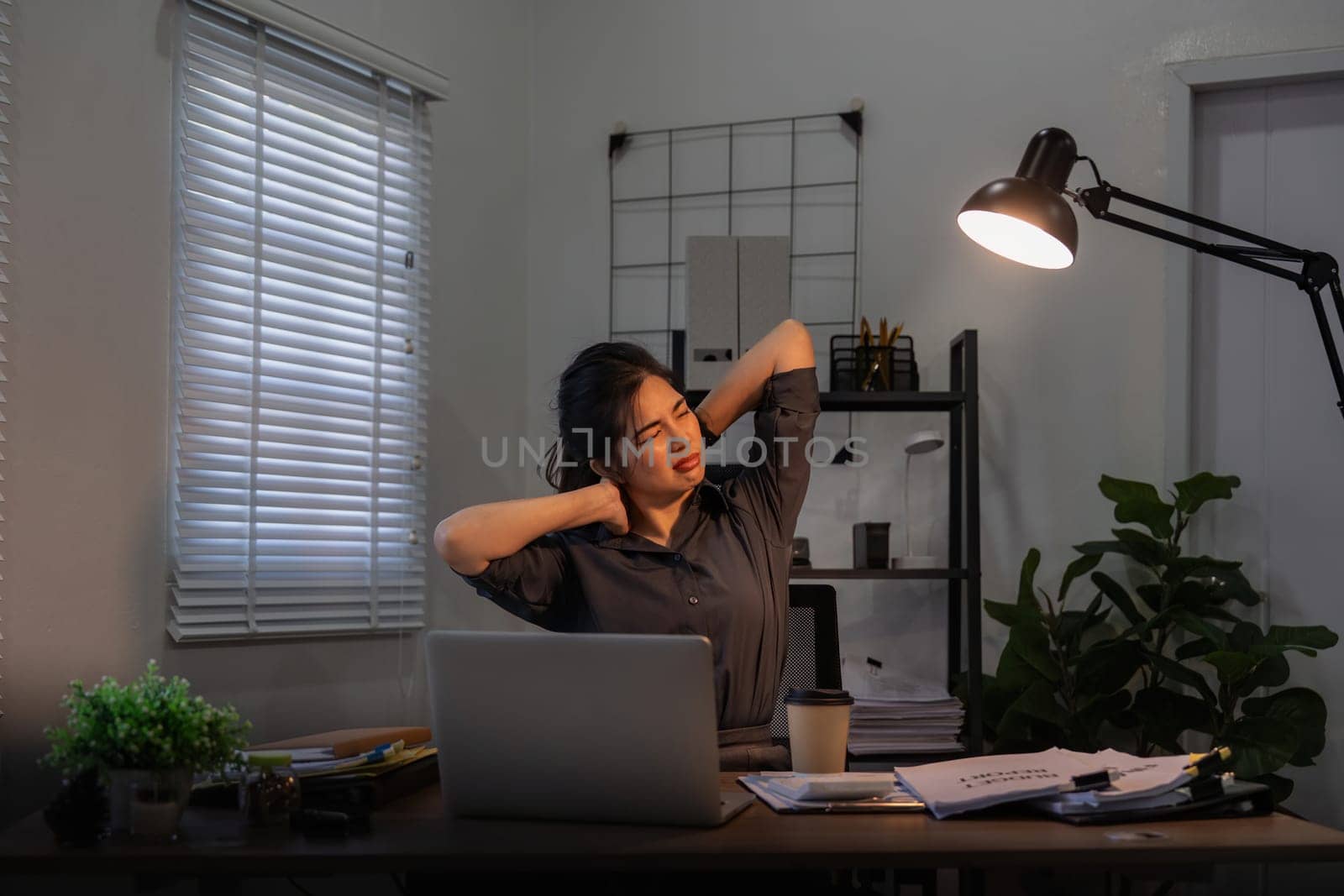 Asian business woman have a neck pain because using the laptop computer and working for a long time at night.