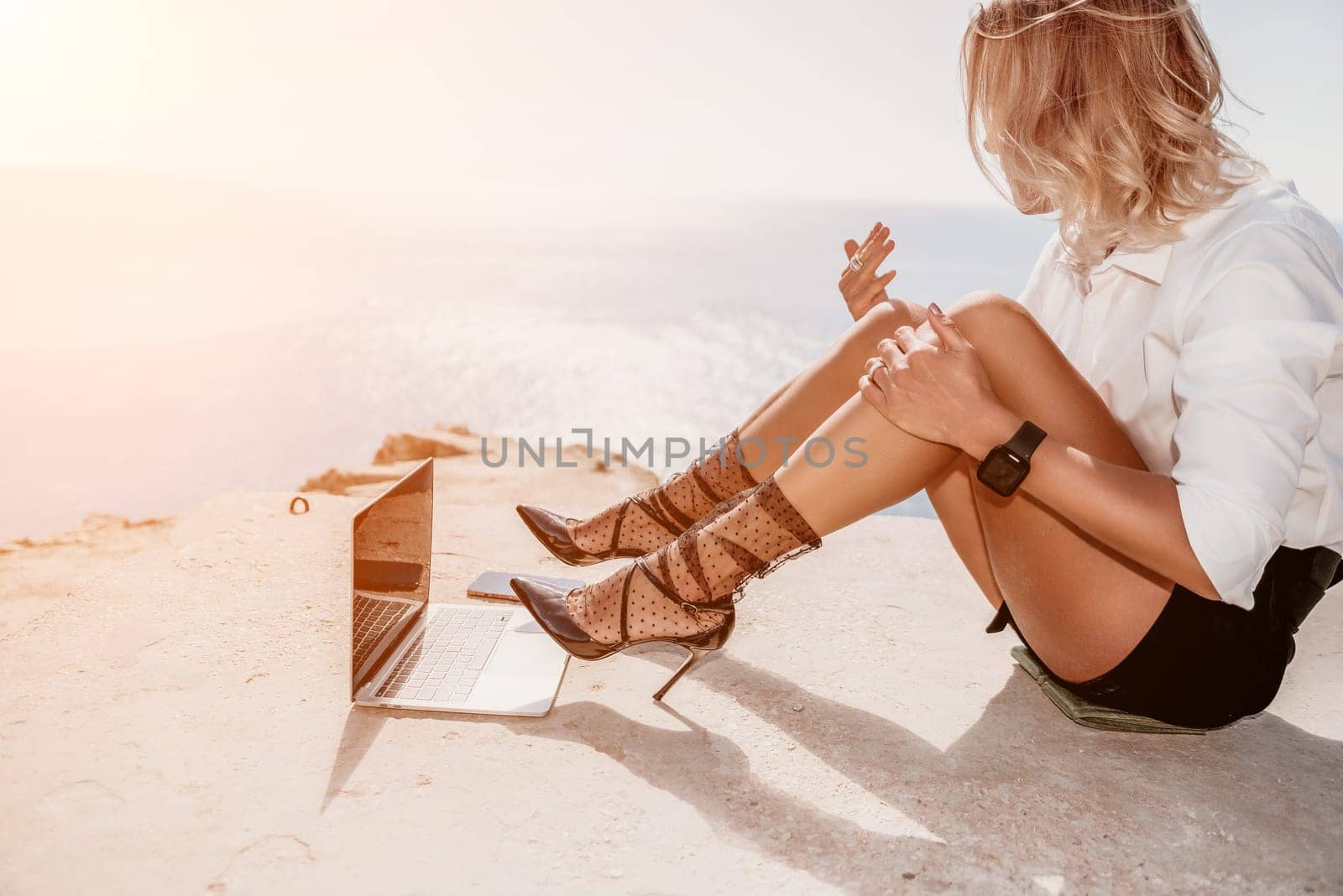 Woman sea laptop. Business woman in yellow hat freelancer with laptop working over blue sea beach. Girl relieves stress from work. Freelance, digital nomad, travel and holidays concept by panophotograph