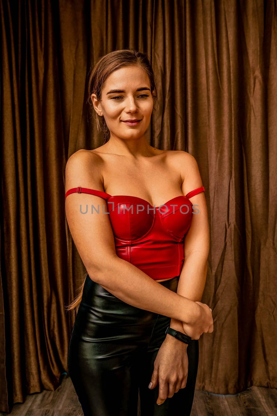 Party girl portrait. Young woman in red corset and black leather pants. Sexy seductive brunette in red and black costume. Role play. Celebration and party. Having fun. by panophotograph