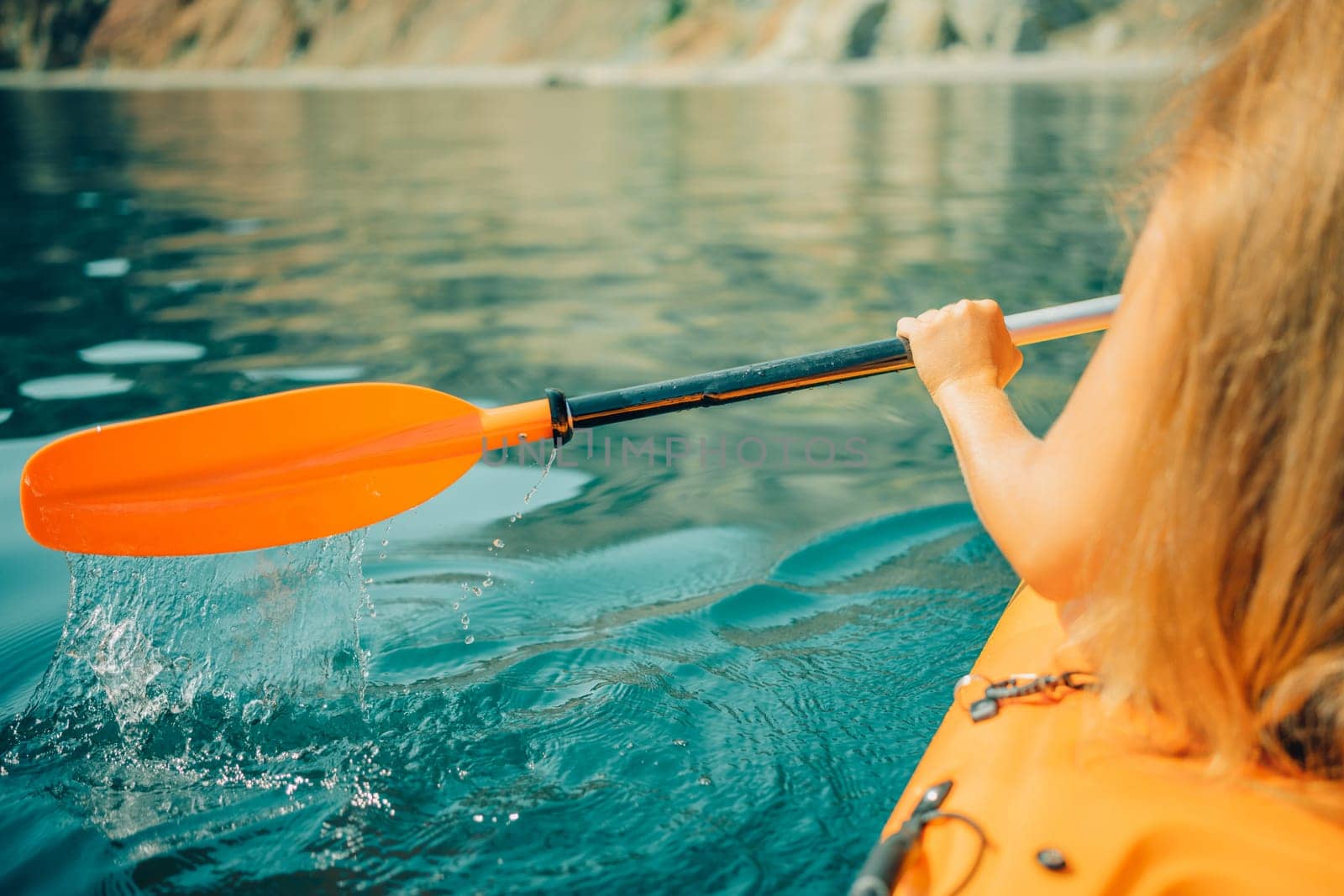 Kayak paddle sea vacation. Person paddles with orange paddle oar on kayak in sea. Leisure active lifestyle recreation activity rest tourism travel.