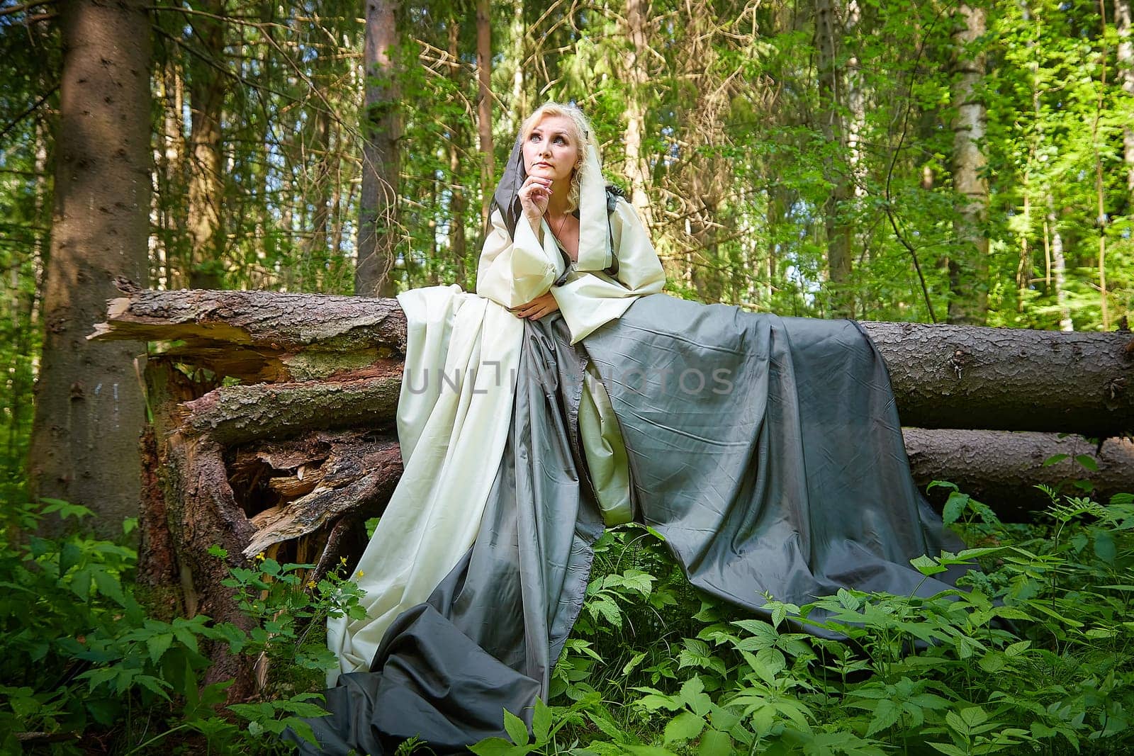 Adult mature woman 40-60 in a green long fairy dress in forest. Photo shoot in style of dryad and queen of nature. Fairy who loves nature in beautiful green summer forest. Concept of caring for nature by keleny