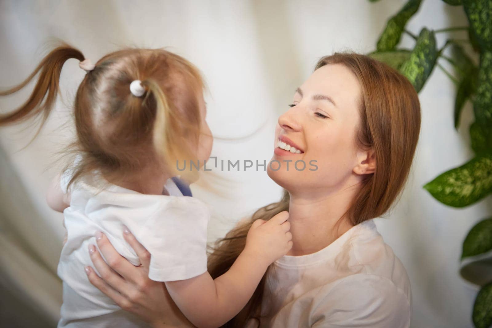 Happy loving family. Mother and daughter child girl playing and hugging in living room with wicker chair