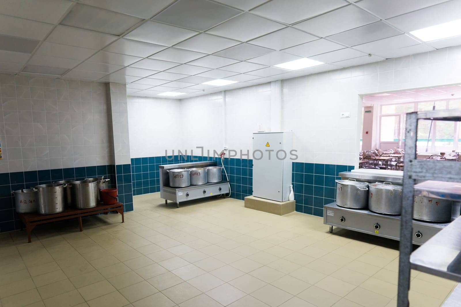 Industrial kitchen in a school restaurant with professional equipment and pans by Zelenin