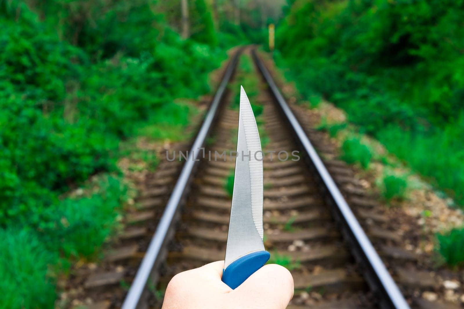 Knife in a hands on the rails, railroad by Zelenin