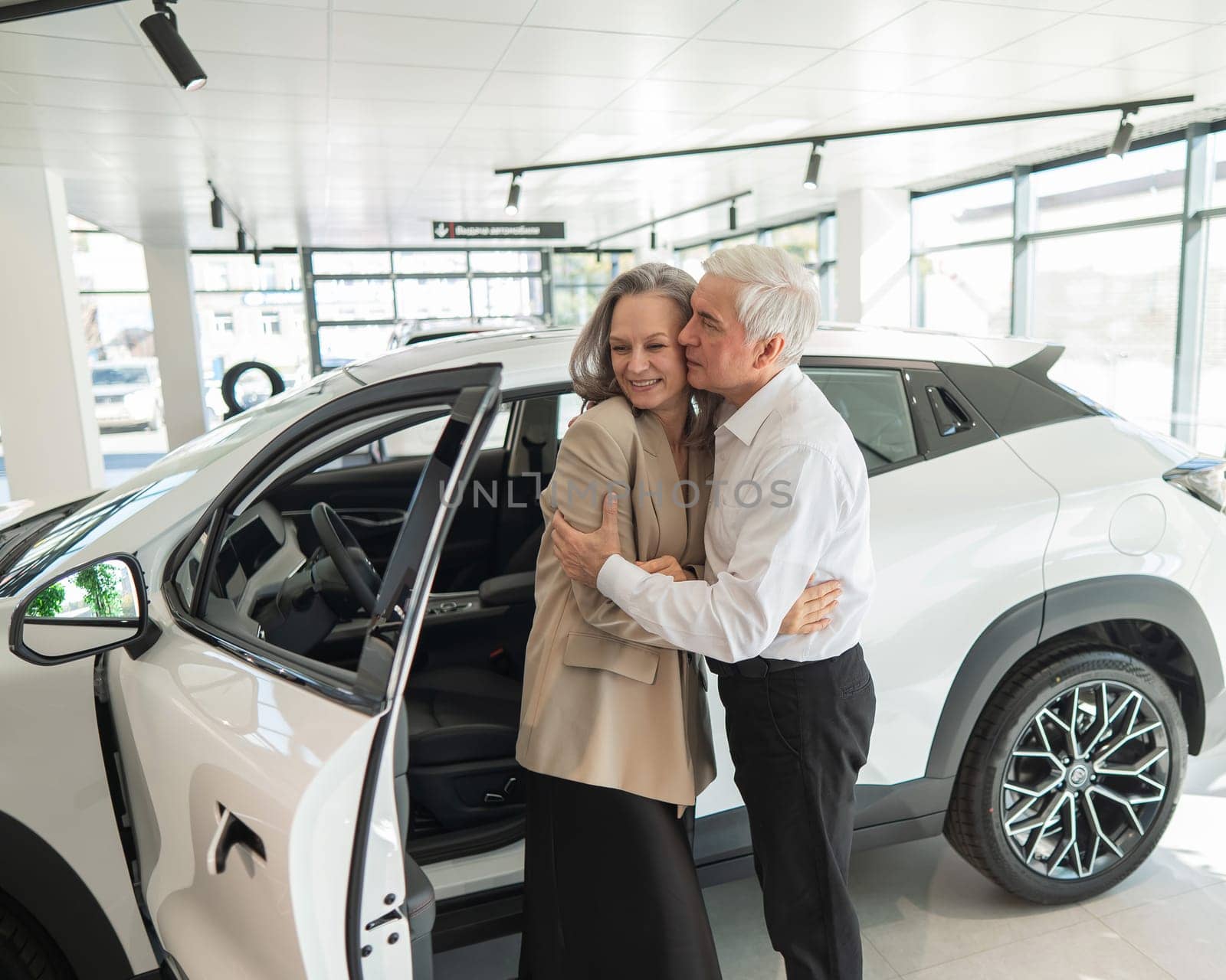 Mature Caucasian couple hugging. Elderly man and woman buying a new car. by mrwed54