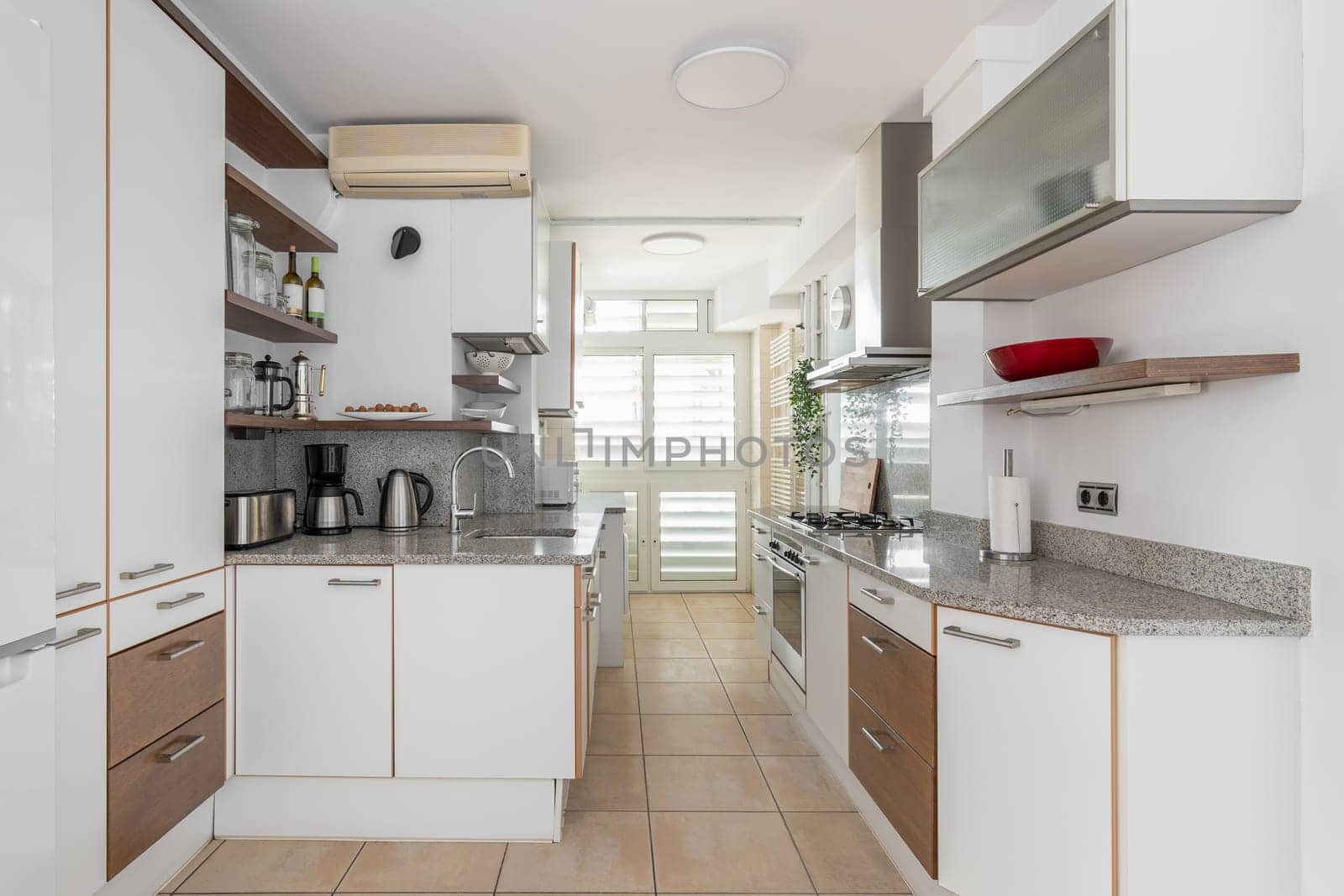 Kitchen zone equipped with cooking appliances and furniture in smart apartment. Idea of limited space living organization in studio flat