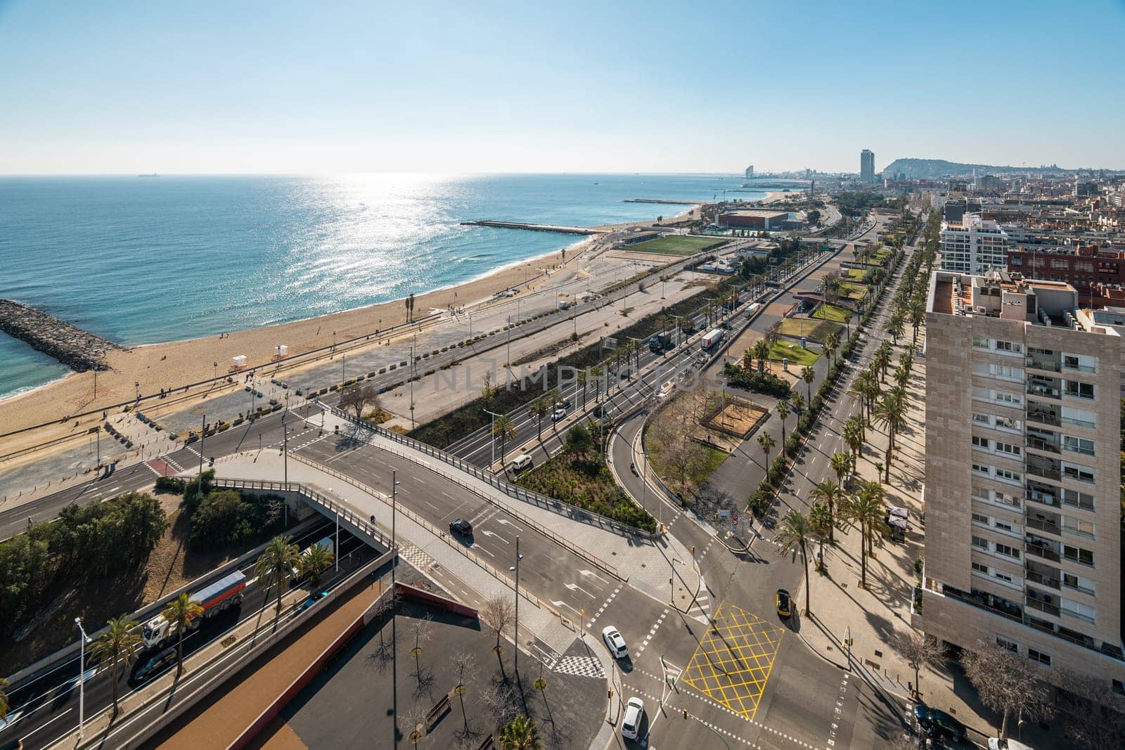 Urban interchange with overpass bridge in Diagonal Mar area in Barcelona. Blue sea and city infrastructure view from luxury apartment window