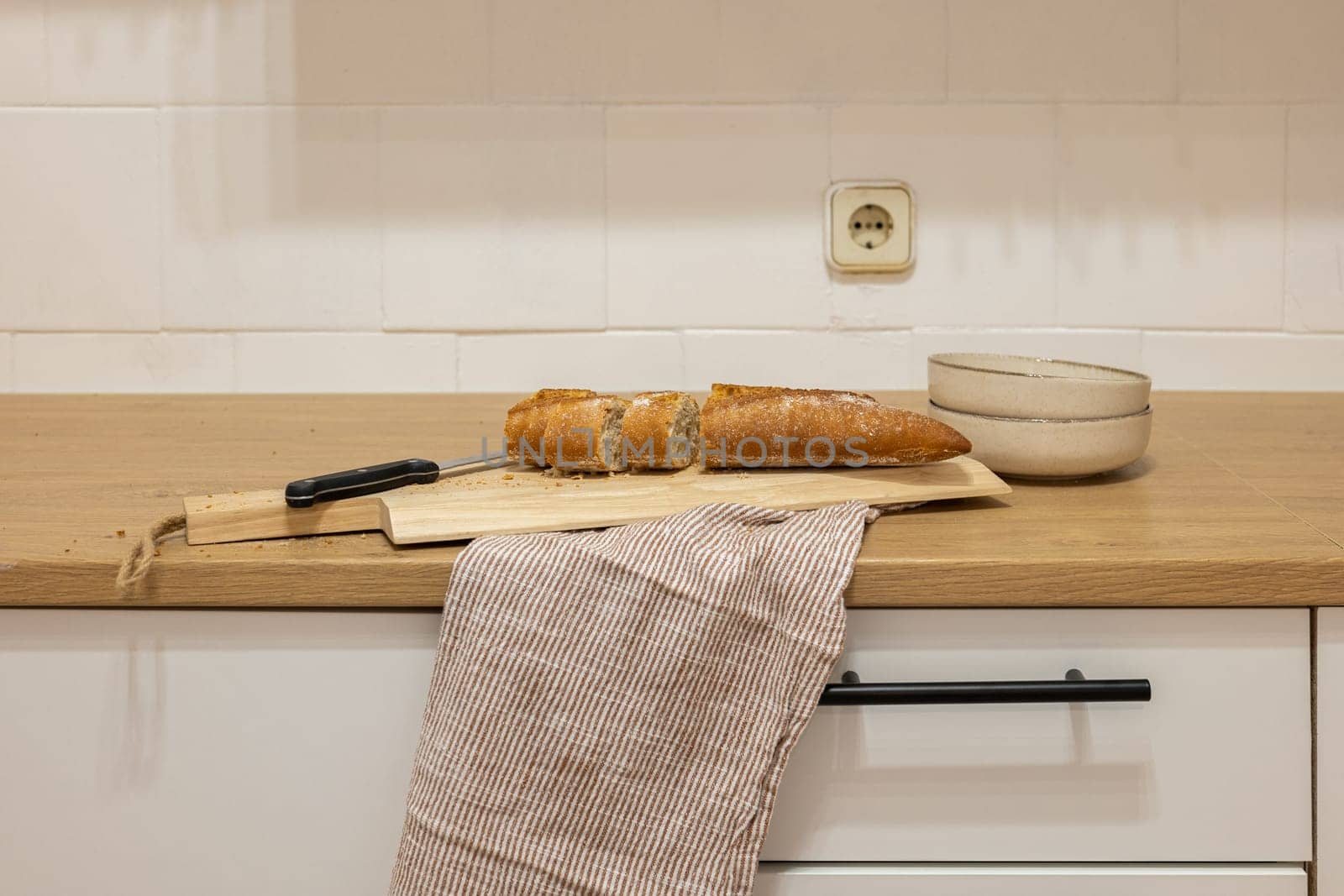 Kitchen table surface with knife and bread on cutting board by apavlin
