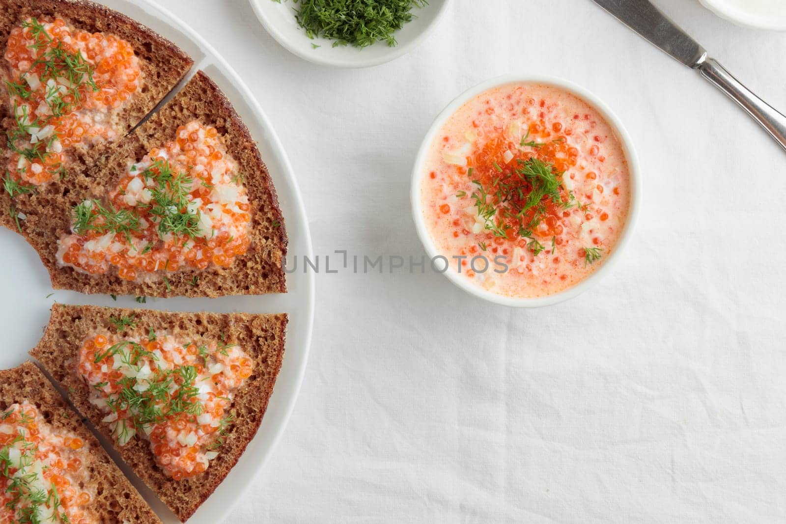 Homemade appetizer with red caviar, sour cream, dill, onion and rye bread on the white table - the traditional finnish recipe for a holiday food, flat lay in minimalistic style, healthy eating concept, horizontal with copy space