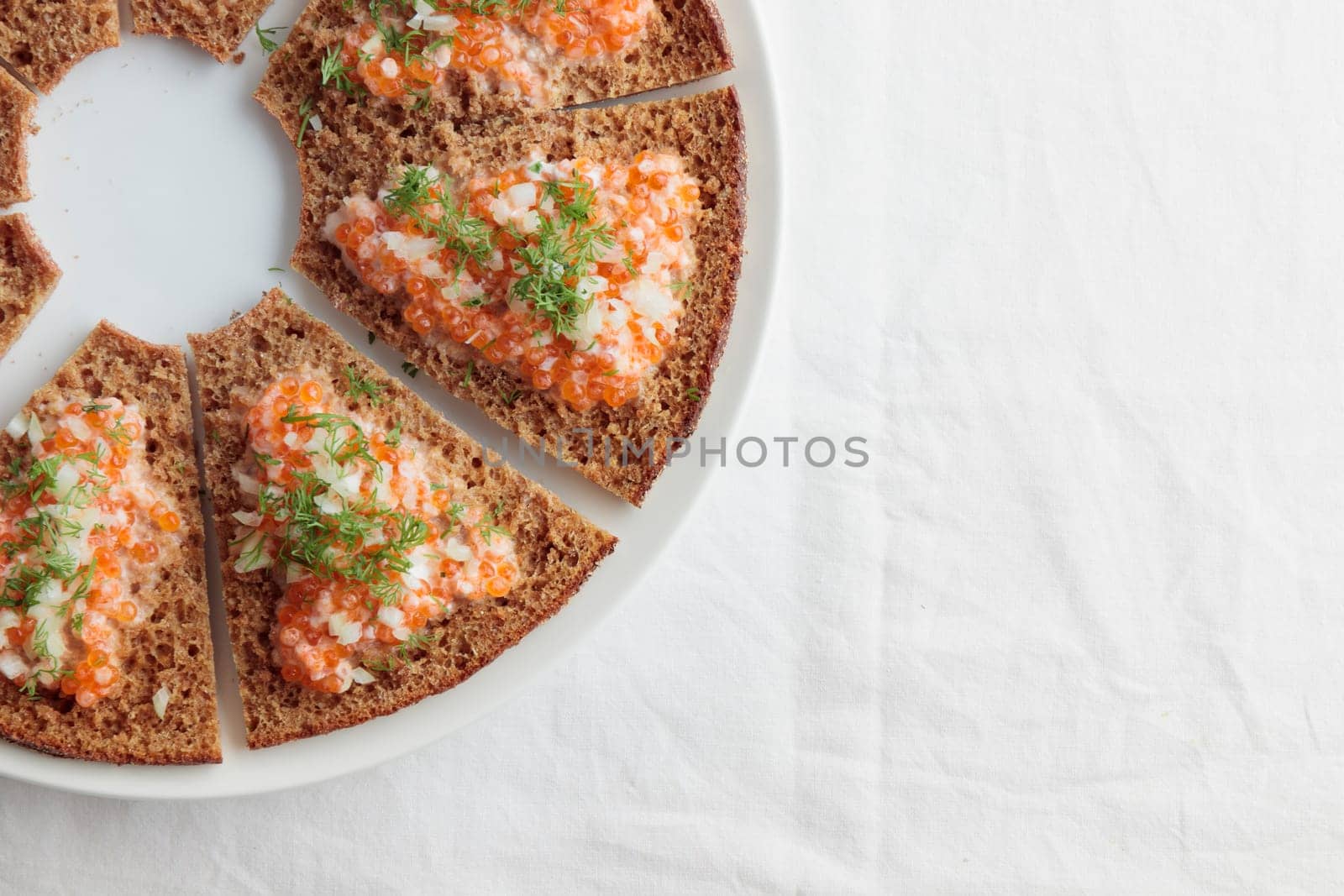 Homemade appetizer with red caviar, sour cream, dill, onion and rye bread on the white table - the traditional finnish recipe for a holiday food, flat lay in minimalistic style, healthy eating concept, horizontal with copy space
