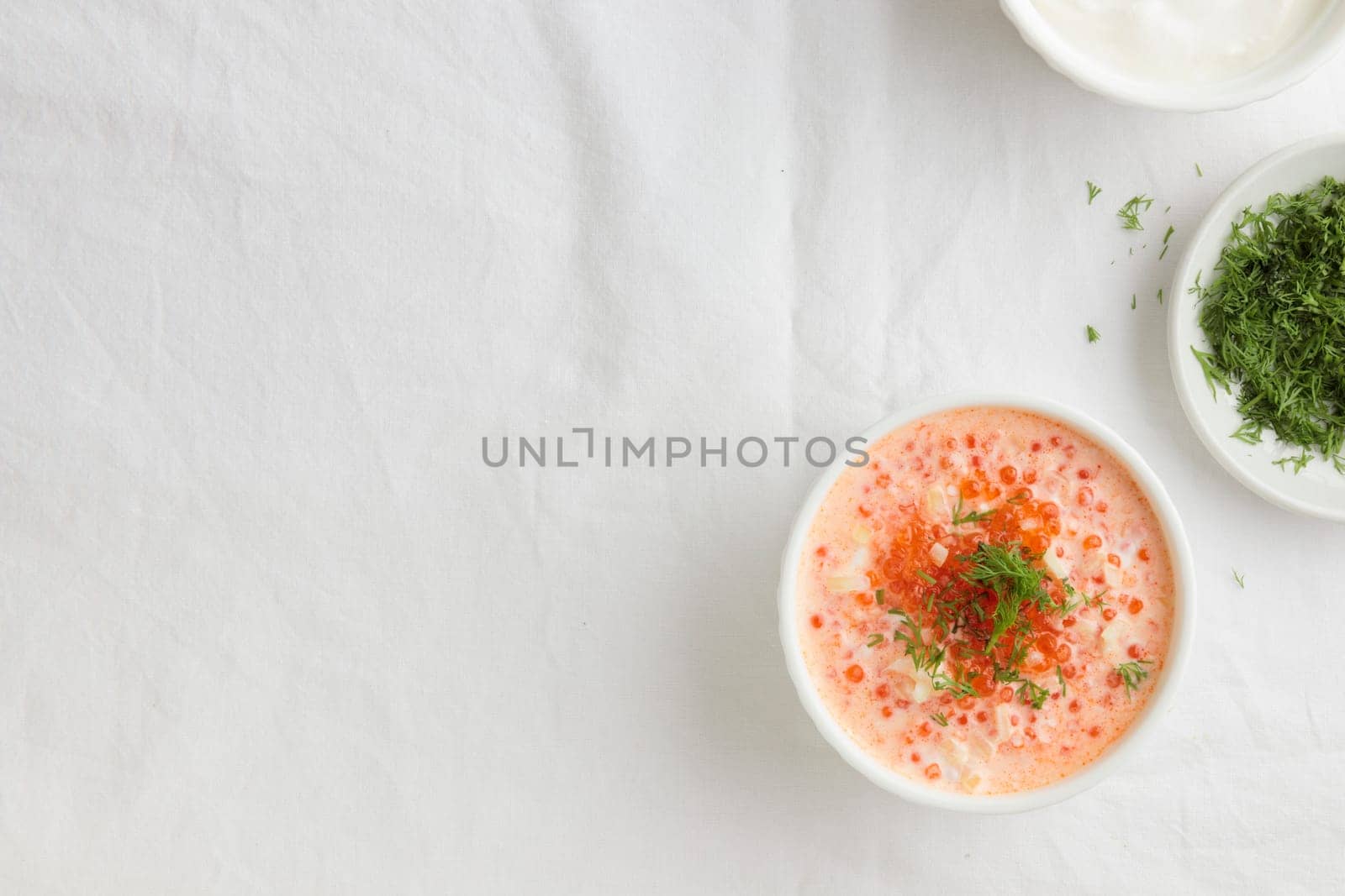 Red caviar with sour cream, dill and onion - the finnish recipe for a holiday food, flat lay on the white table in minimalistic style with copy space by Gudzar