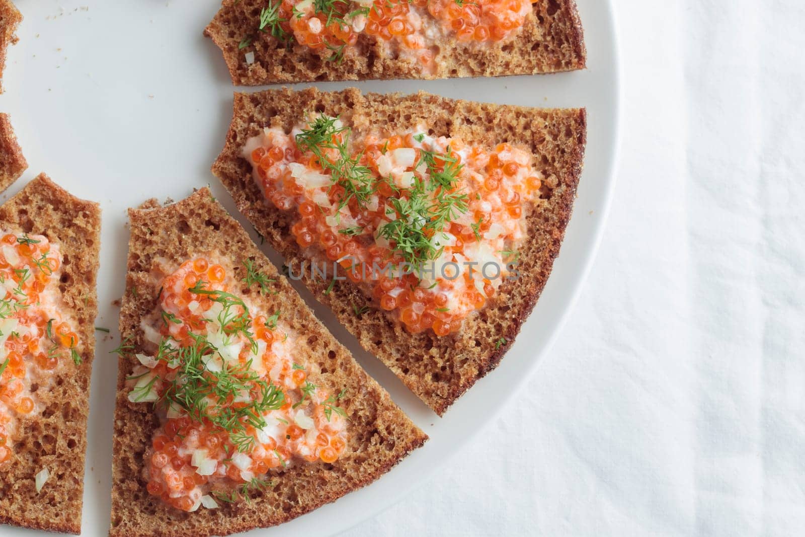 Appetizer with red caviar, sour cream, dill, onion and rye bread on the white table - the finnish recipe for a holiday food, flat lay in minimalistic style by Gudzar