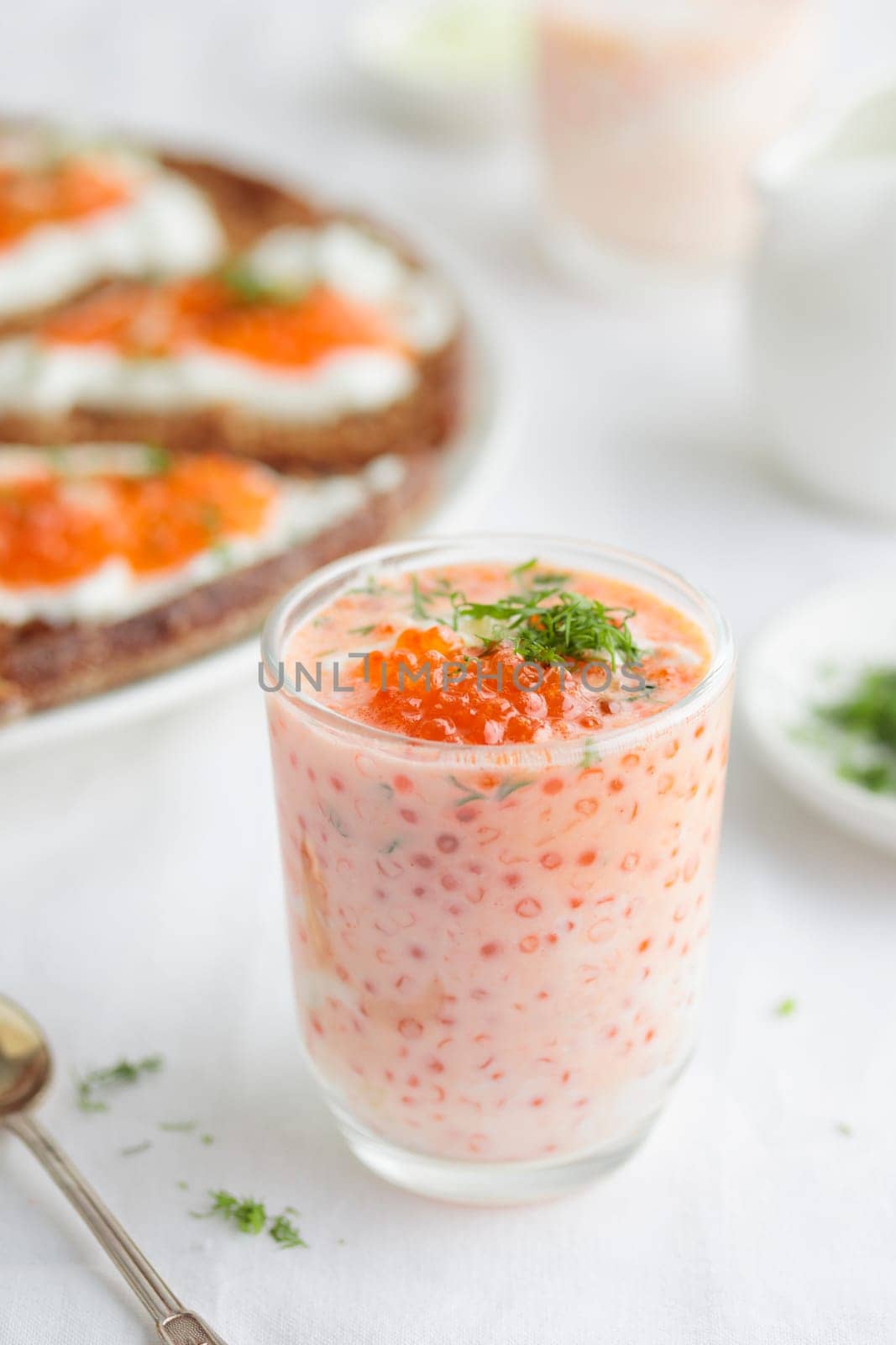 Appetizer with red caviar, sour cream, dill, onion and rye bread on the white table - the finnish recipe for a holiday food, close up in minimalistic style by Gudzar