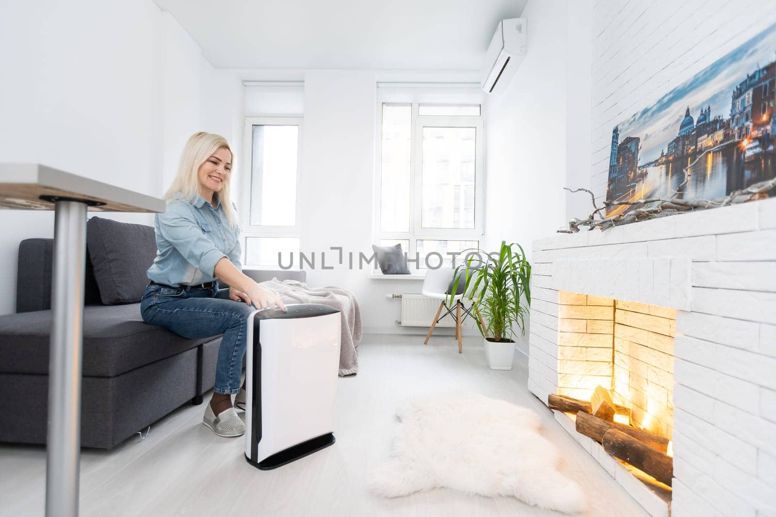 Woman relaxing at home with working air humidifier on the foreground. Concept of home air humidification.