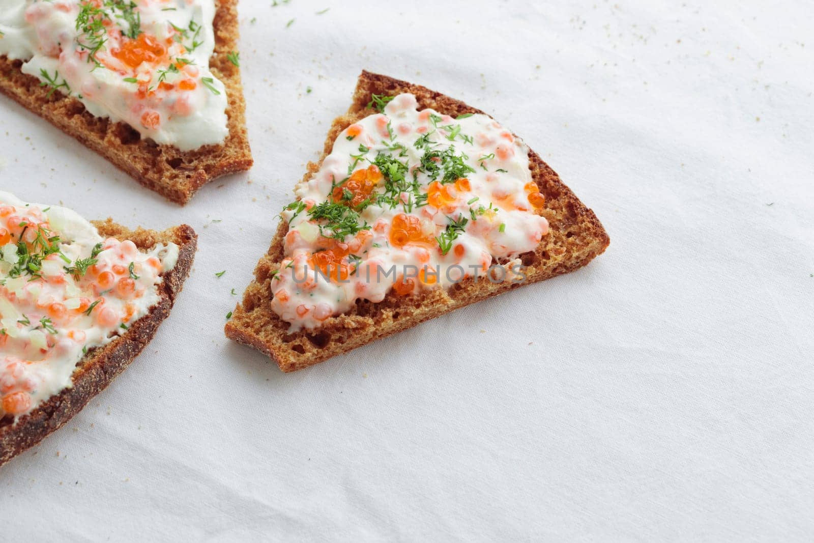 Homemade appetizer with red caviar, sour cream, dill, onion and rye bread on the white table - the traditional finnish recipe for a holiday food, in minimalistic style, healthy eating concept, horizontal