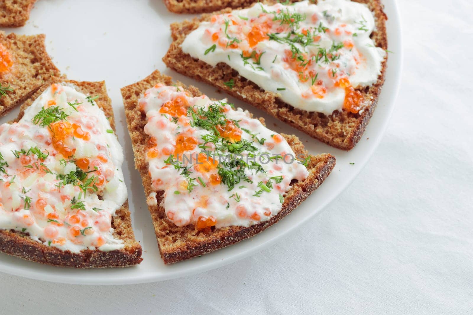 Homemade appetizer with red caviar, sour cream, dill, onion and rye bread on the white table - the traditional finnish recipe for a holiday food, in minimalistic style, healthy eating concept, horizontal