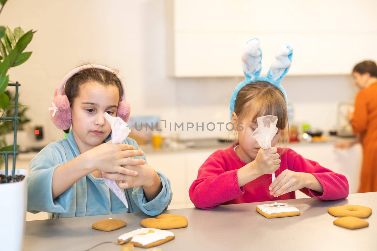 two beautiful sisters decorate and eat delicious cakes at a wooden table.