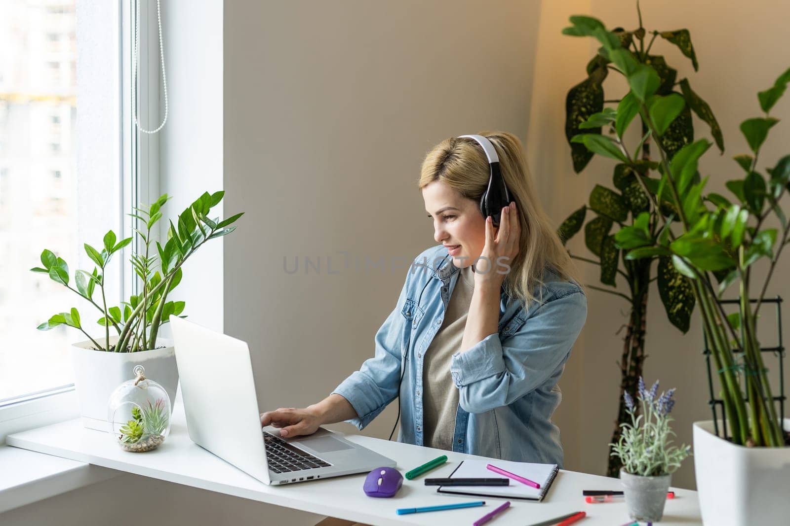 Attractive happy young girl student studying, sitting at the desk, using laptop computer, having video chat, waving by Andelov13