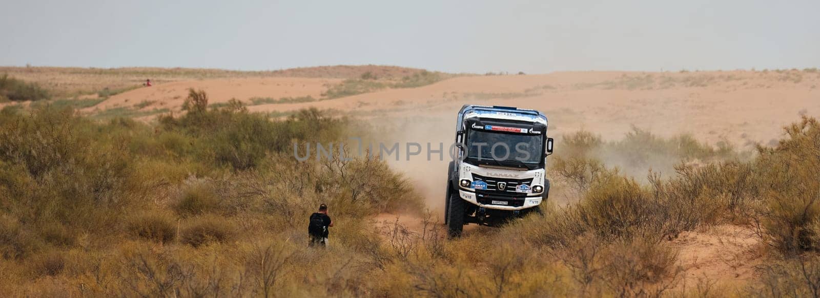 Sports truck KAMAZ gets over the difficult part of the route during the Rally raid in sand. Photographer shoots truck racing. 14.07.2022 Kalmykia, Russia.