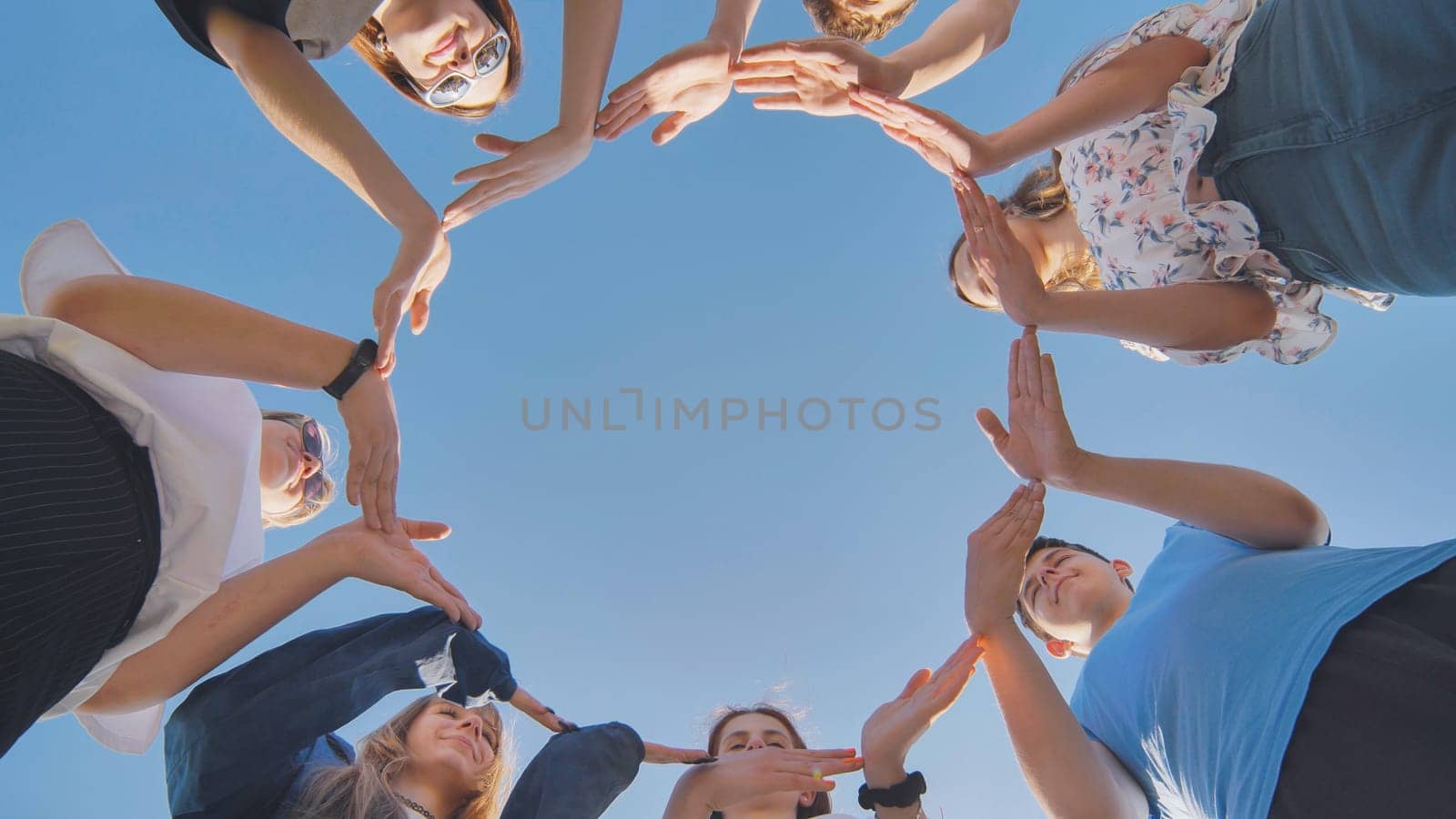 School friends make a big circle with their hands. by DovidPro