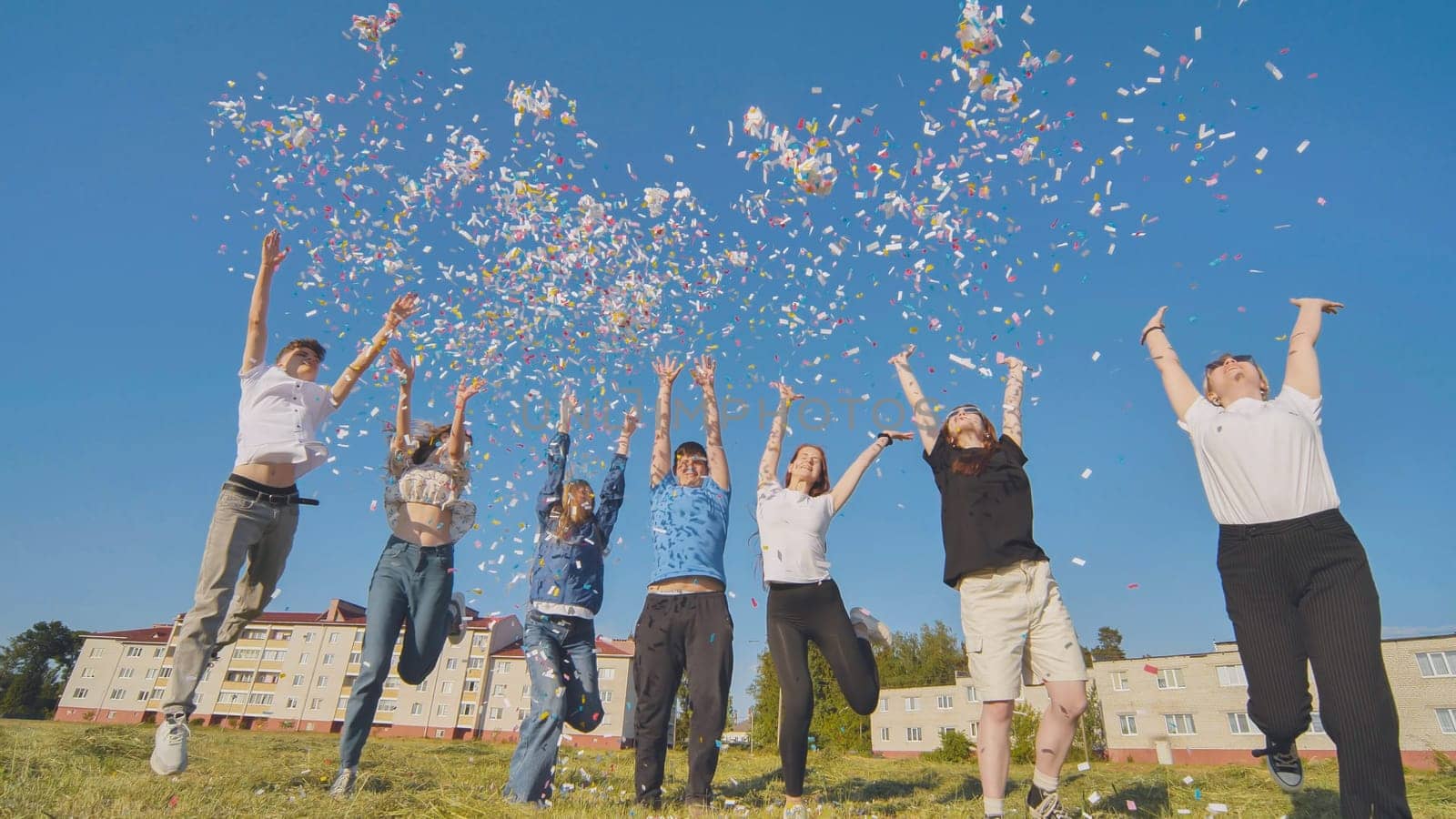 Friends toss colorful paper confetti from their hands. by DovidPro