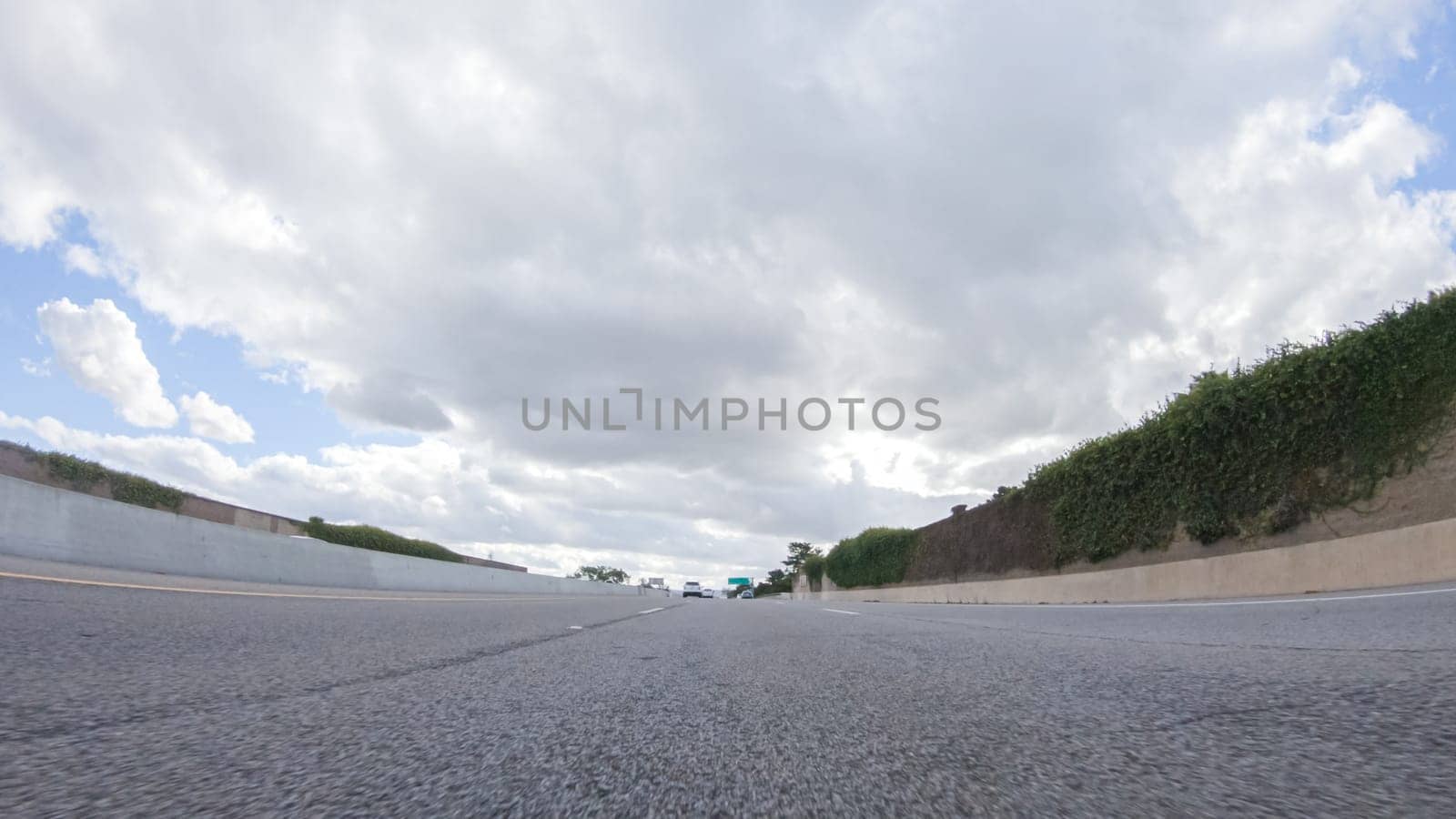 On a cloudy winter day, a car smoothly travels along Highway 101 near Santa Maria, California, under a cloudy sky, surrounded by a blend of greenery and golden hues.