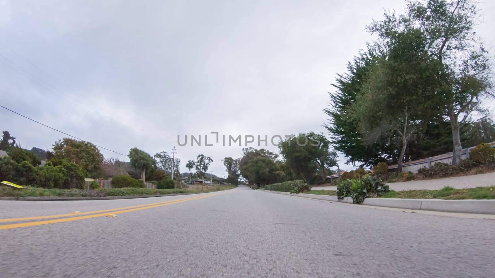 Vehicle navigates the streets of Morro Bay, California, during a cloudy winter day. The atmosphere is moody and serene as the overcast sky casts a soft light on the charming buildings and quiet streets of this coastal town.
