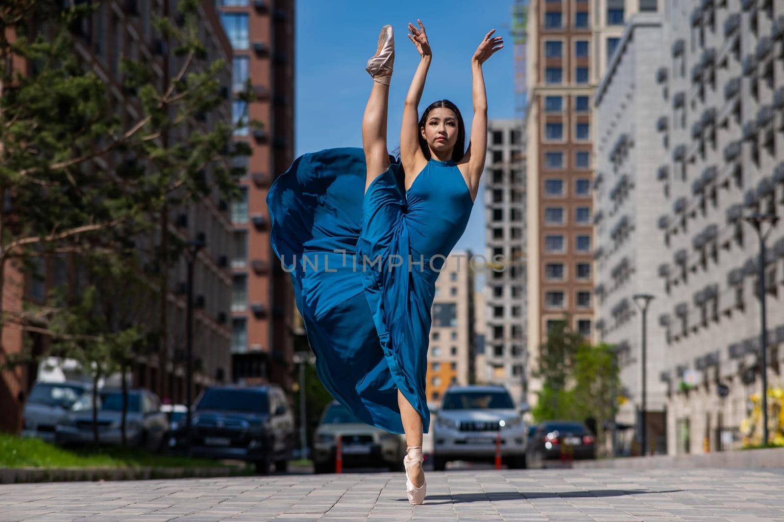 Beautiful Asian ballerina dancing outdoors. Urban landscape