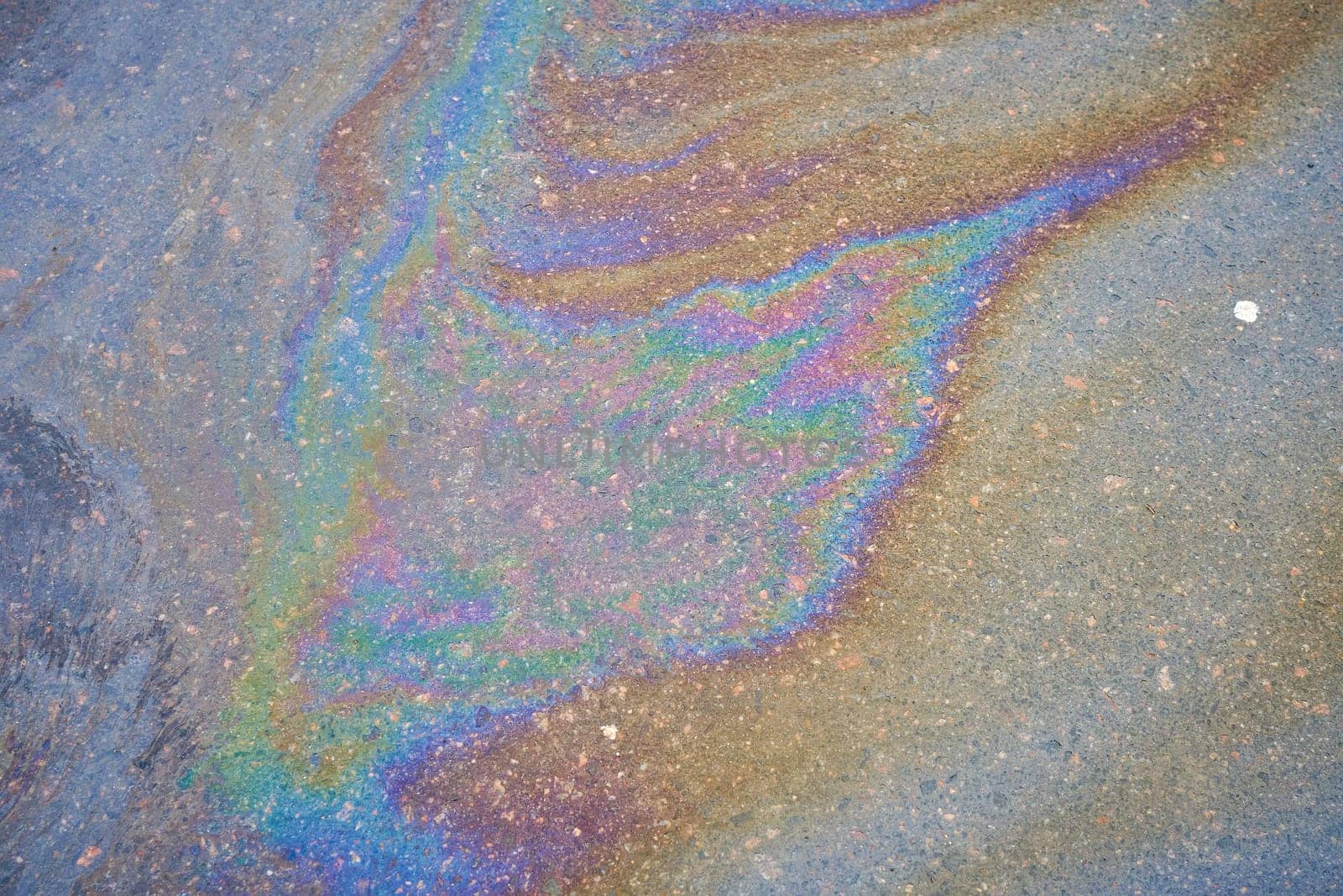 Petroleum fuel spilled on wet asphalt, abstract background.