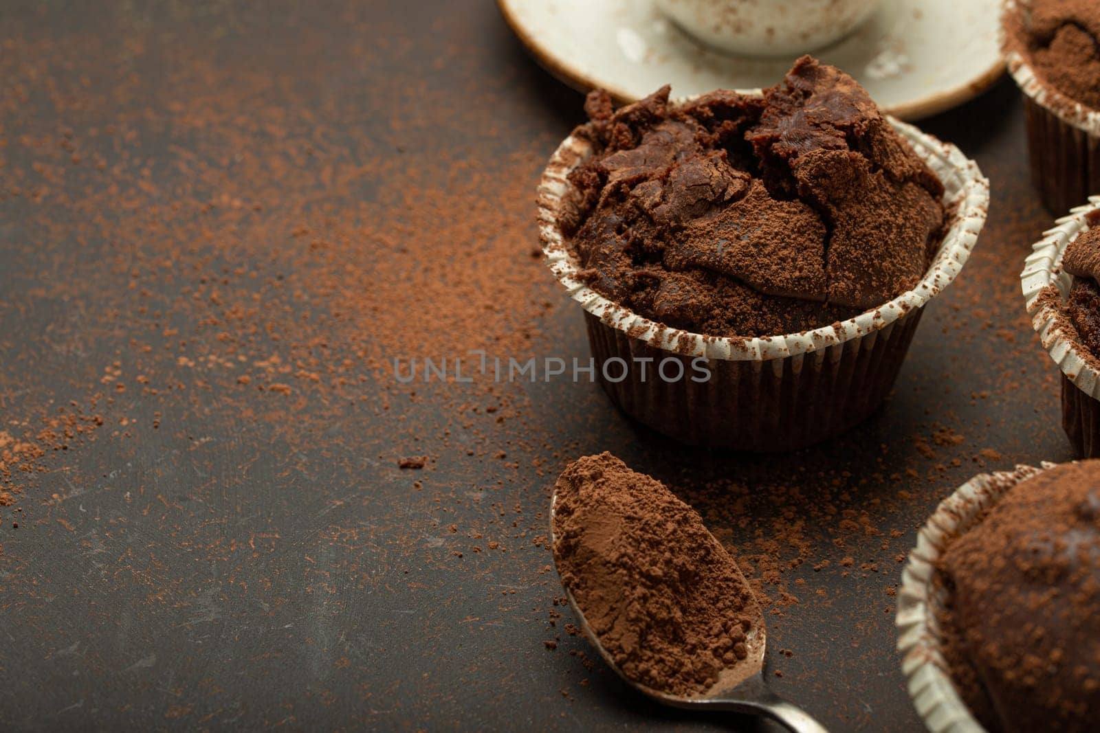 Chocolate and cocoa browny muffins with coffee cappuccino in cup angle view on brown rustic stone background, sweet homemade dark chocolate cupcakes, space for text by its_al_dente