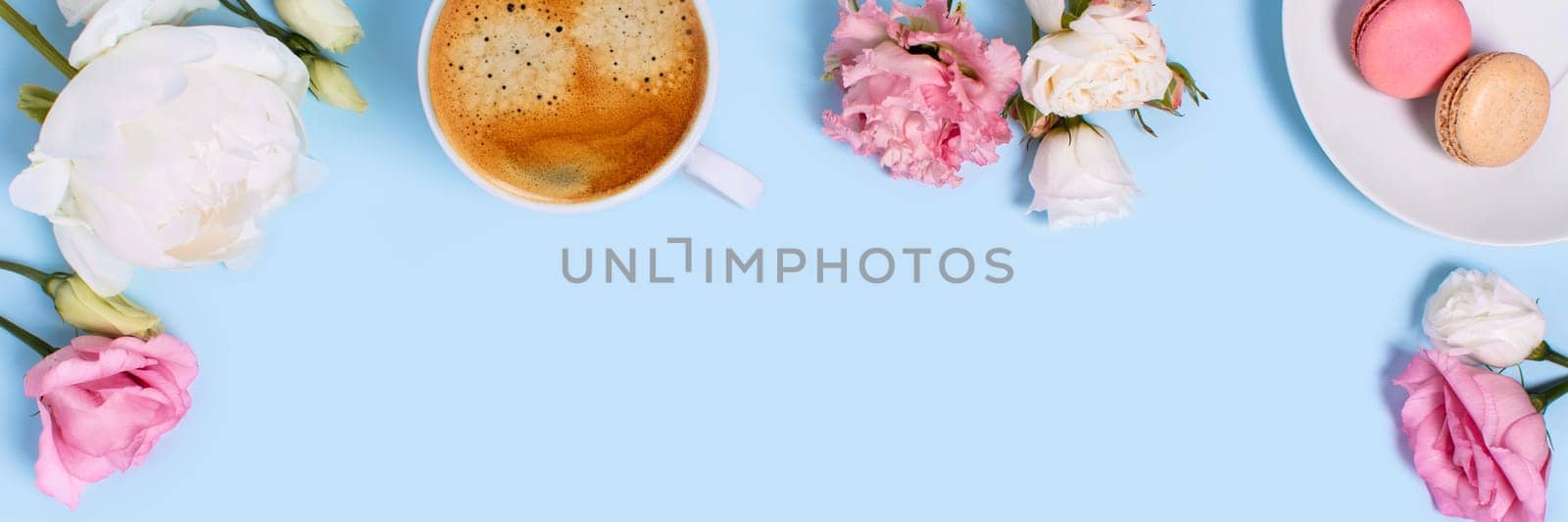 Blue background with macaroons and a Cup of coffee surrounded by peonies and roses. Top view with space for your text.