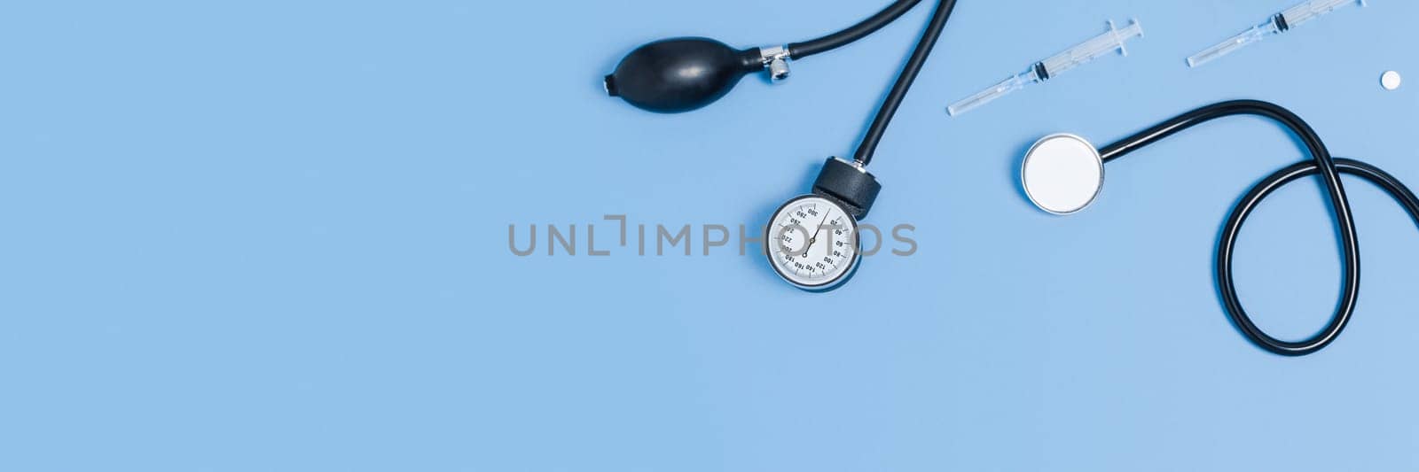 Medical blue background with different accessories: stethoscope, thermometer, syringe and tablets.