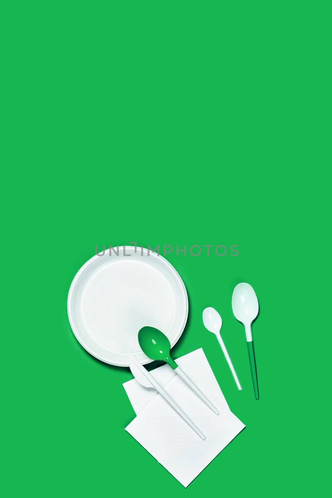 Picture of white plastic spoons and plates on blue background. Flat lay, top view, copy space.