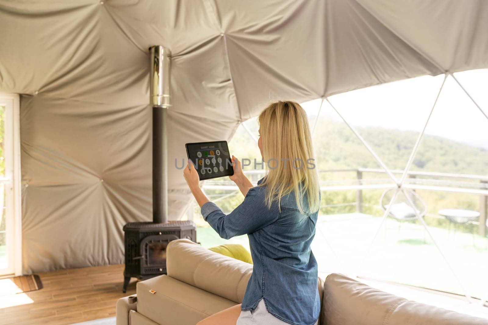 woman holding a tablet with the smart home application in a glamping dome tent domestic by Andelov13