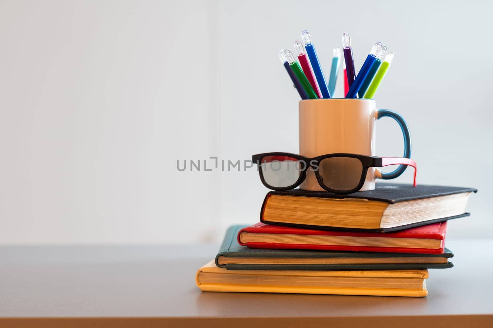 a stack of books and a cup with pencils by Andelov13