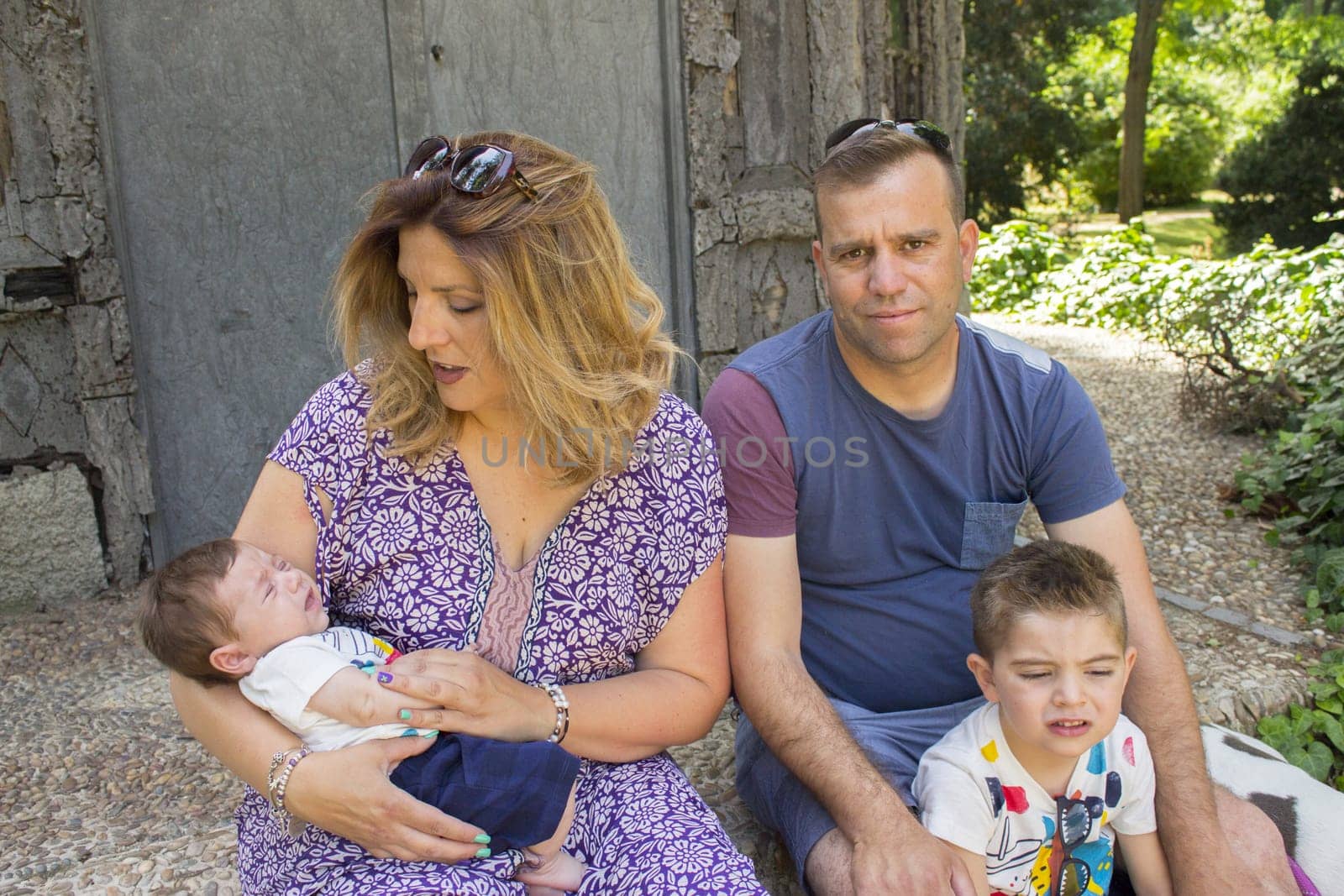 Family consisting of parents and two children. Sitting on some stairs.