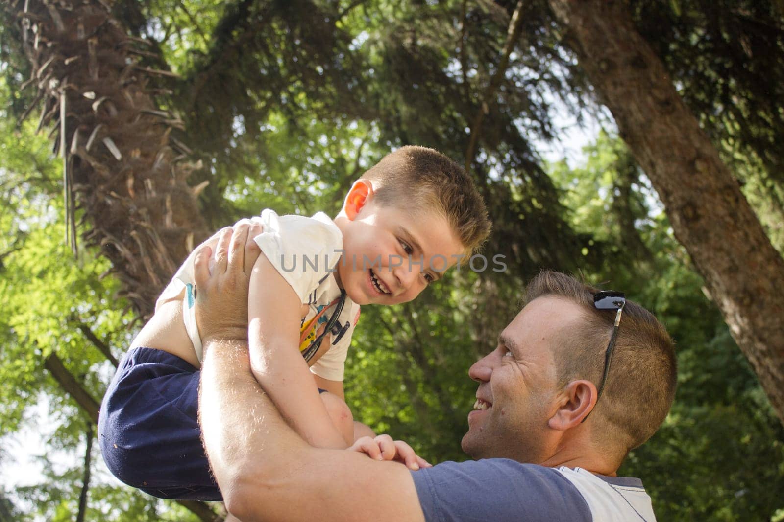 Father with son holding him up in the air. Smiling