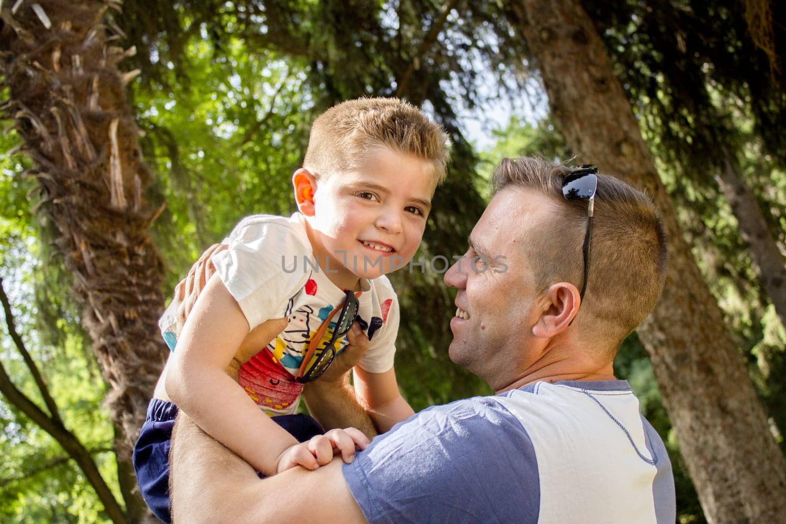 Father with son holding him up in the air. Smiling