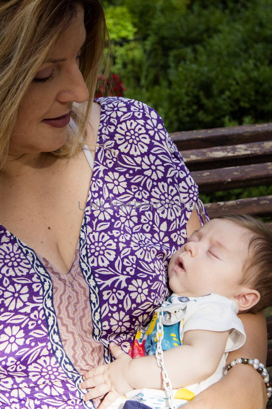 Baby sleeping in his mothers arms. Sweet scene