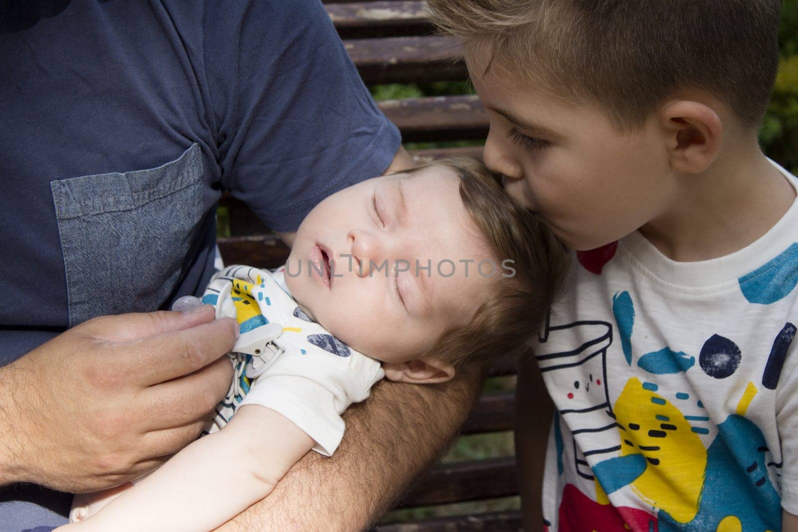 Four year old boy kissing his two month old brother. Sweet scene