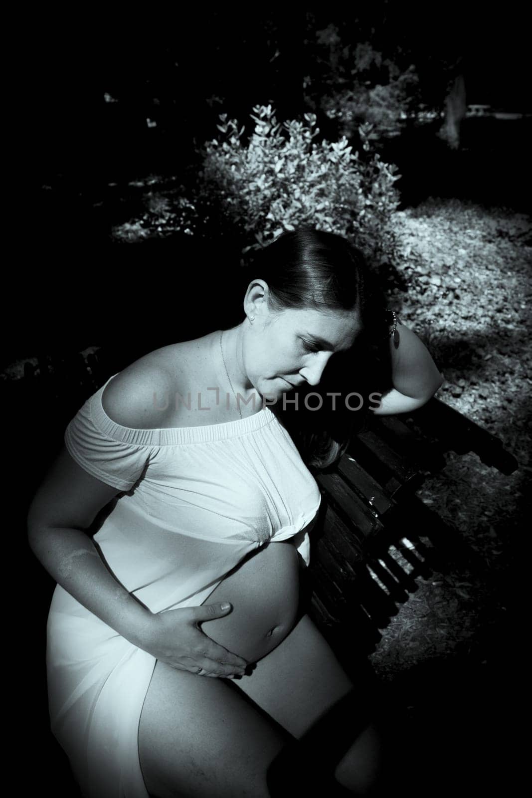 Seven month pregnant woman standing dressed in pink. Happy expression