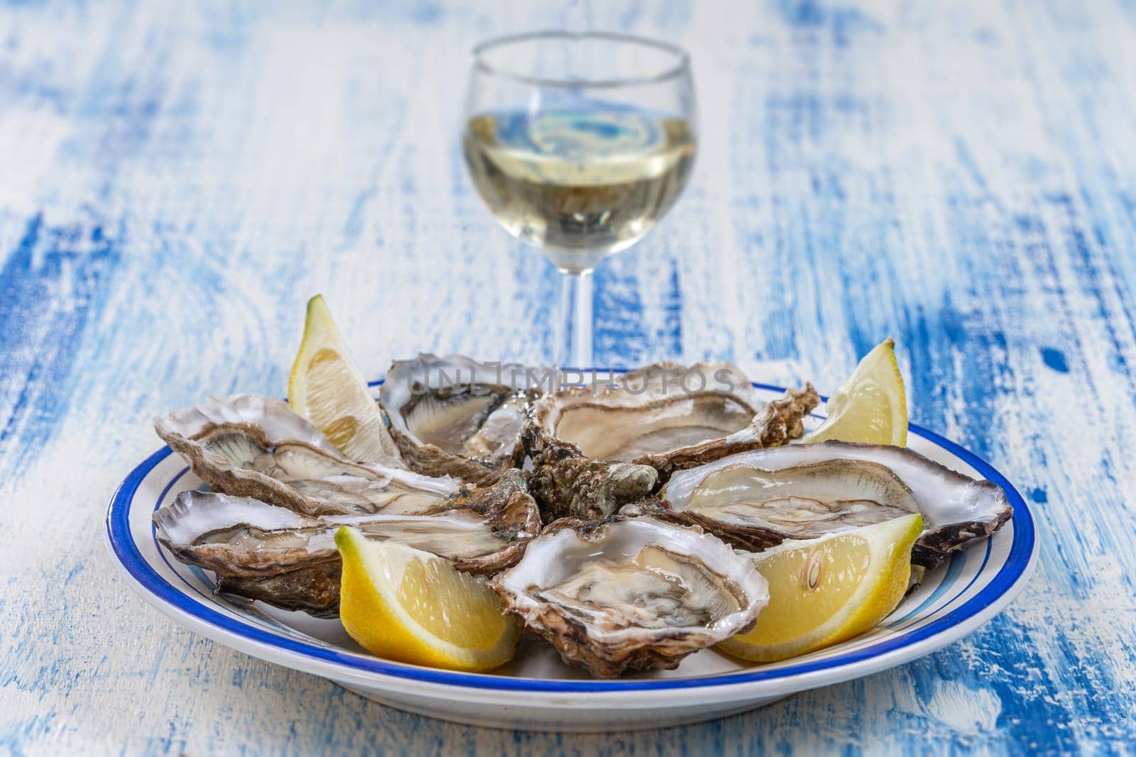 Oysters and glass of white wine in a restaurant wooden table background